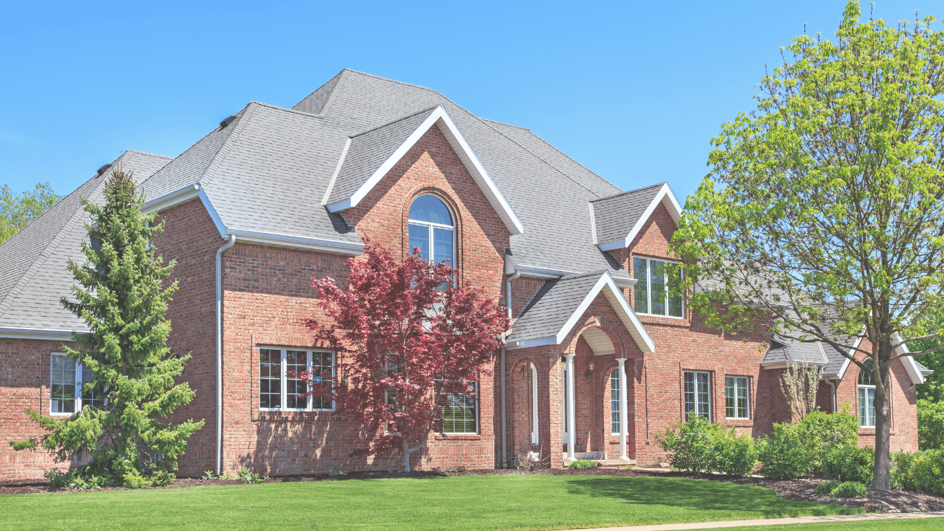 Beautiful brick house with green lawn and trees.